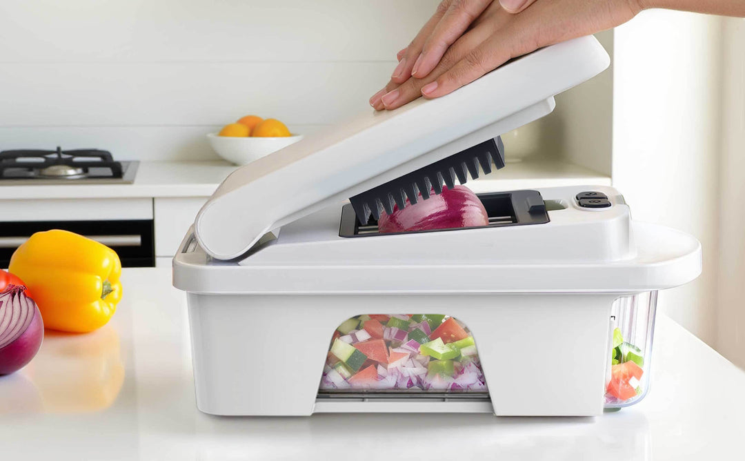 Mueller Vegetable Chopper with hands pressing down the chopper lid with a red onion being chopped on a kitchen countertop.