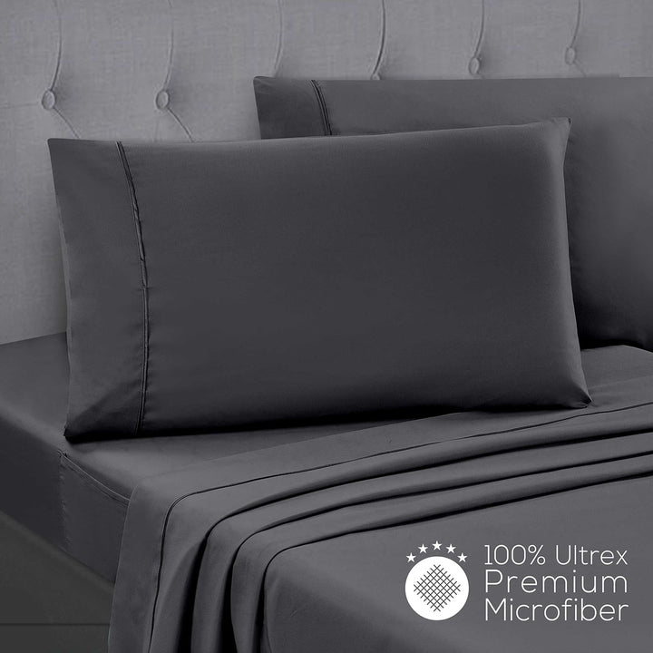 Gray bed sheets and pillowcases on a bed with a tufted headboard, featuring 100% Ultrex Premium Microfiber label.