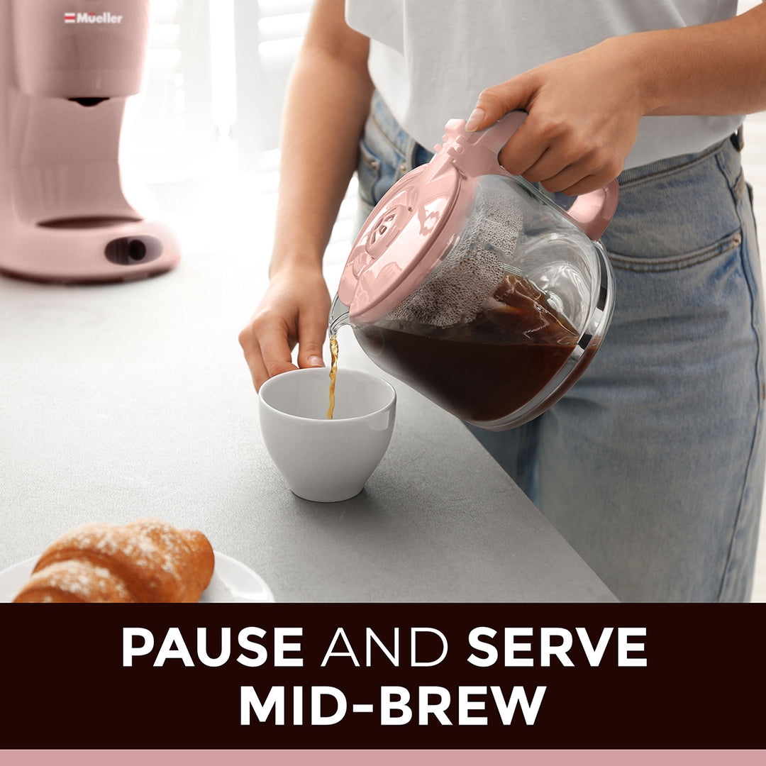 Person pouring coffee from a glass carafe into a white cup on a kitchen counter.