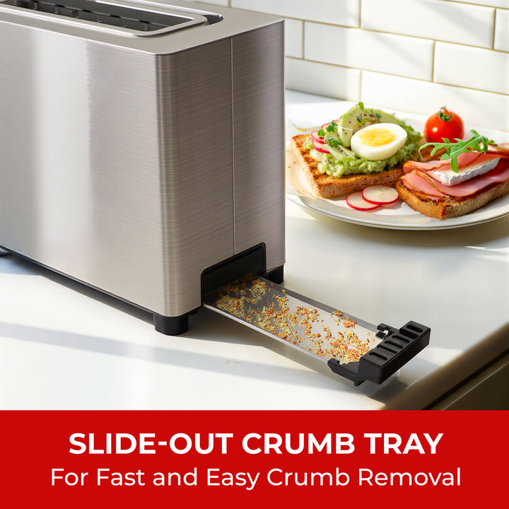Stainless steel toaster with slide-out crumb tray and a plate of toast with avocado and tomato on a white countertop.