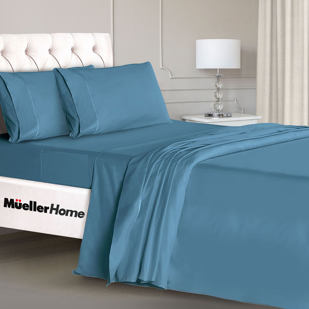 Blue bed sheets and pillows on a bed with 'Mueller Home' branding.