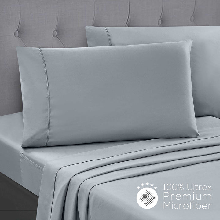 Gray bedding set with flat sheet, fitted sheet, and pillowcases on a bed.