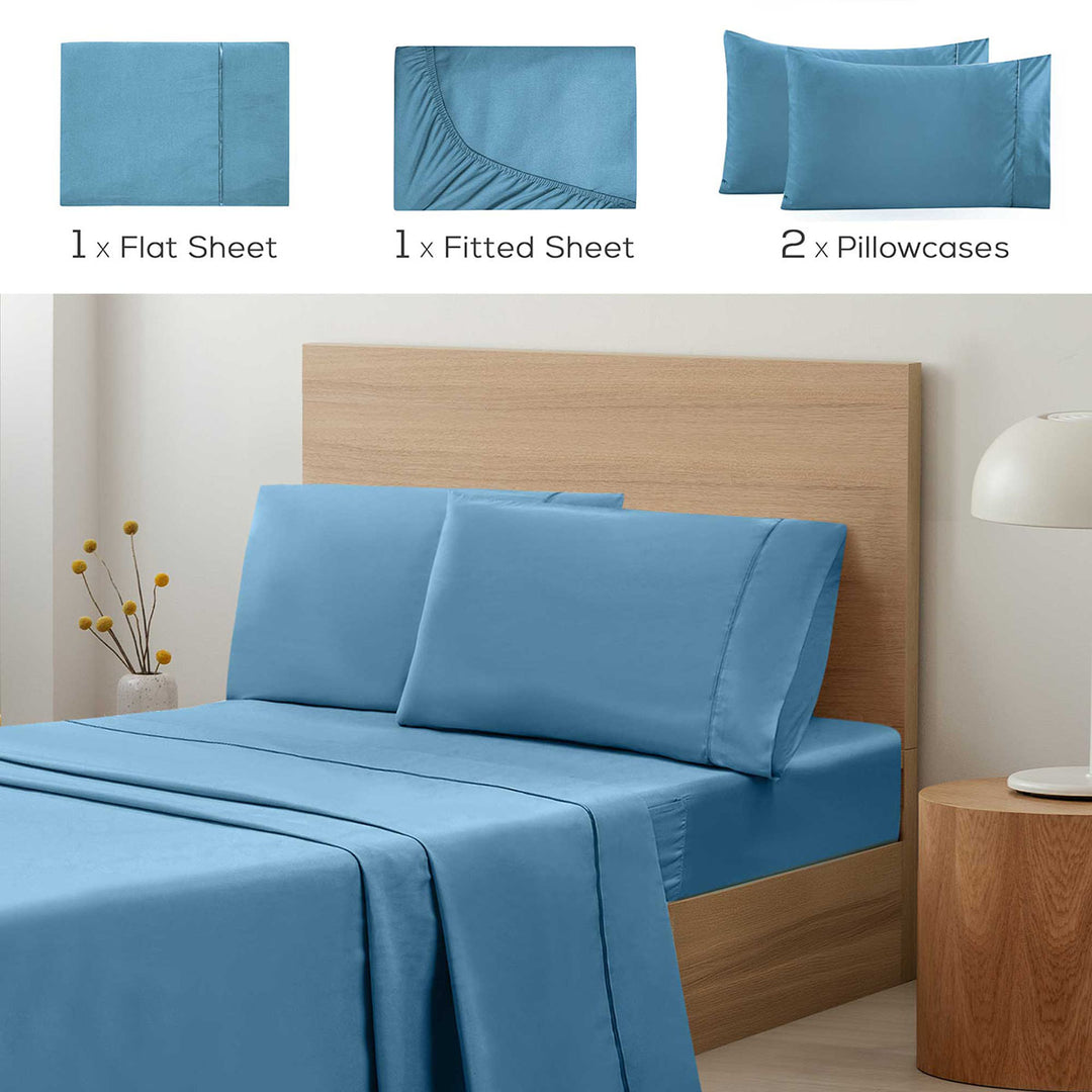 Blue bed sheet set with flat sheet, fitted sheet, and pillowcases on a bed.