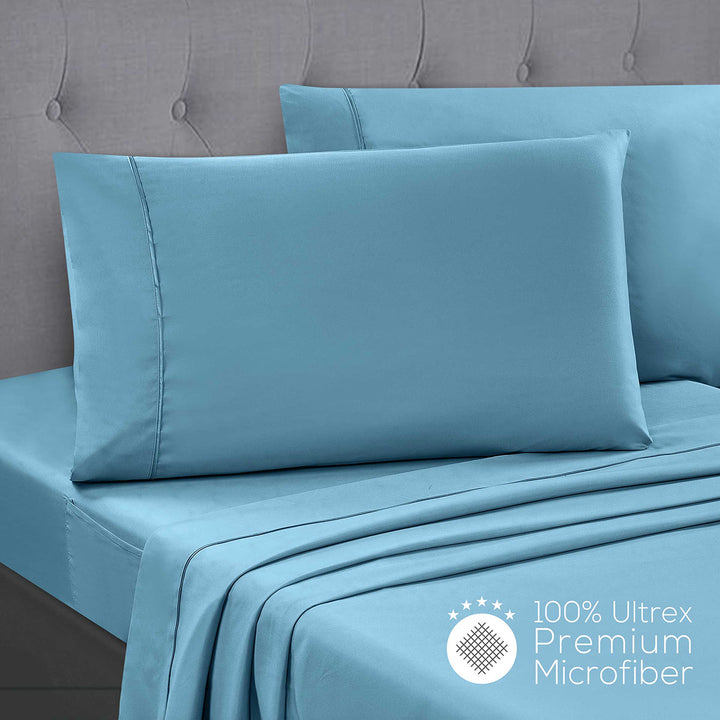 Teal bed sheets and pillowcases on a bed with a gray headboard, featuring 100% Ultrex Premium Microfiber label.