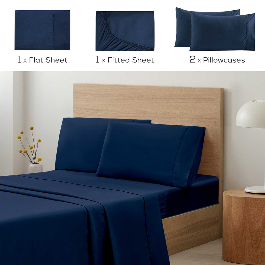 Navy blue bedding set with flat sheet, fitted sheet, and pillowcases on a bed.