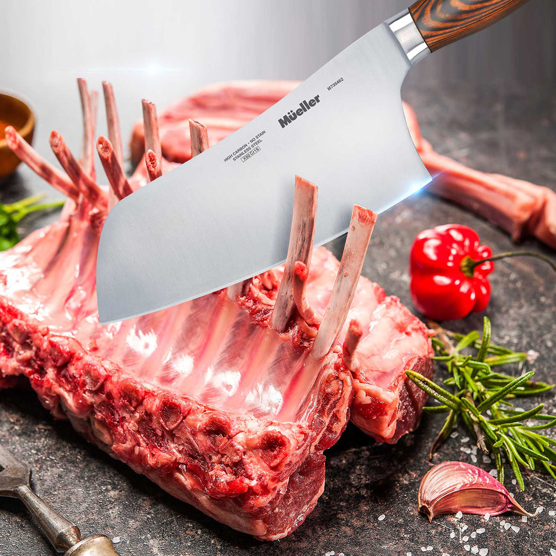 Mueller Cleaver-Chinese-Chefs-Knife-Pakkawood-Handle cutting into a raw lamb rack on a dark surface with vegetables.