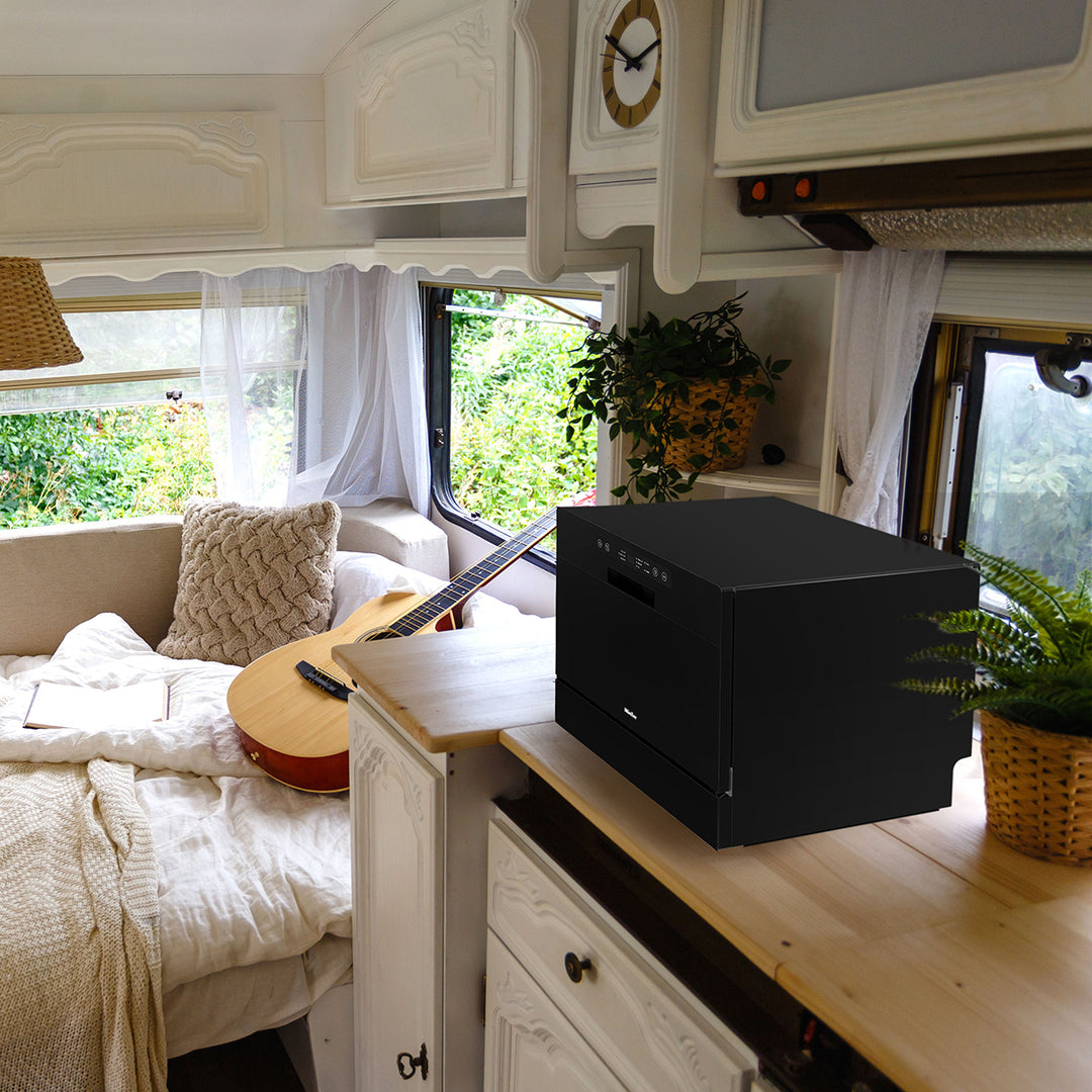 Black countertop dishwasher on a wooden surface in a cozy living room with a guitar and decor.
