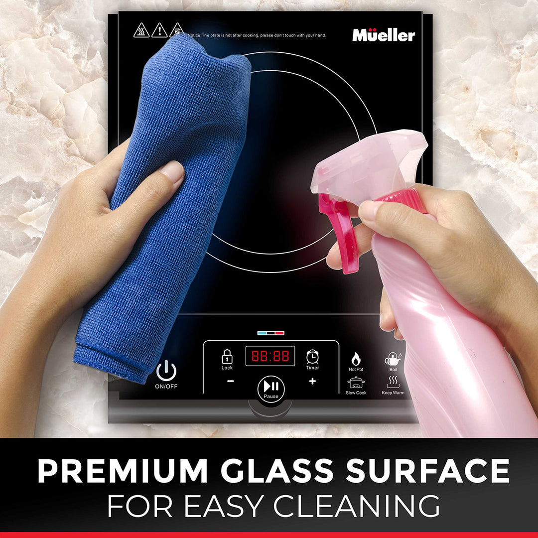 Person cleaning a Mueller glass cooktop with a blue cloth and pink spray bottle.