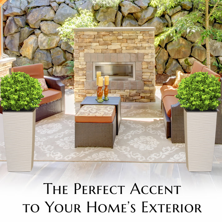 Outdoor patio with stone fireplace, chairs, and plants against a stone wall.