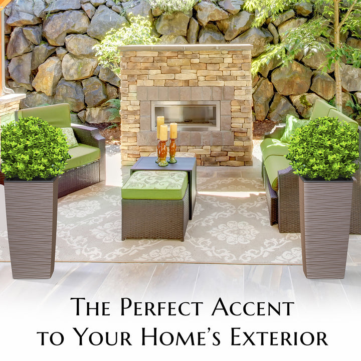 Outdoor seating area with stone fireplace, chairs, and plants against a stone wall.