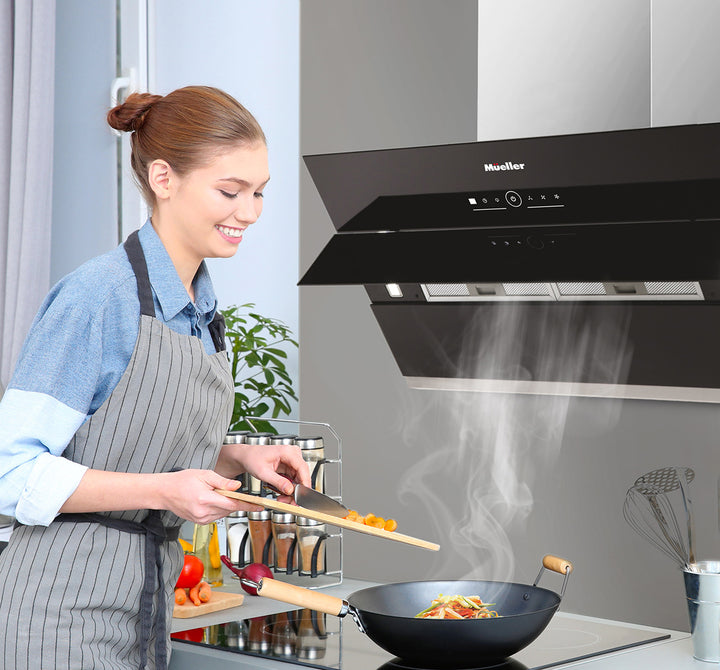 Woman cooking in a kitchen with a black Mueller range hood.