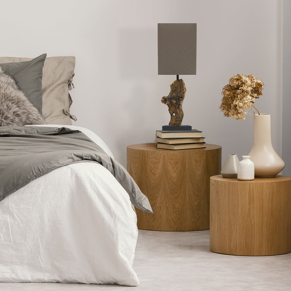 Modern bedroom with wooden side tables, lamp, and decorative items.