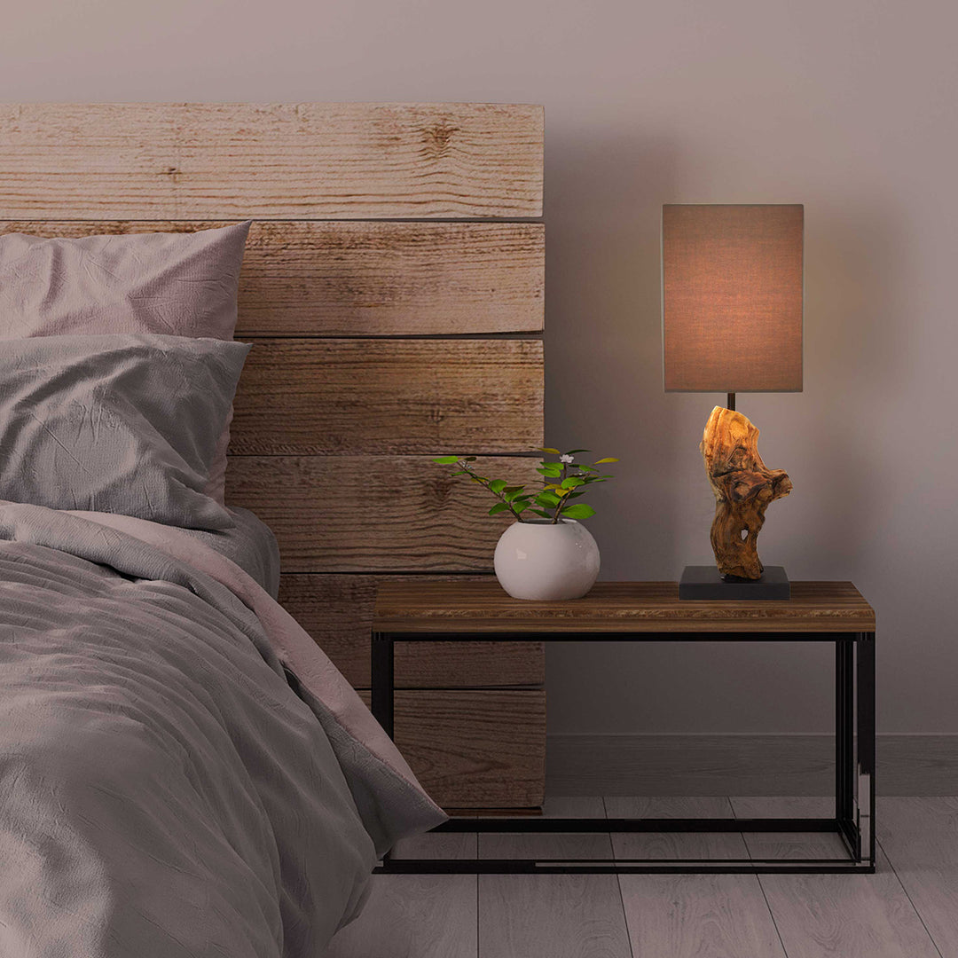 Bedroom with wooden headboard, gray bedding, and a nightstand with a lamp and plant.