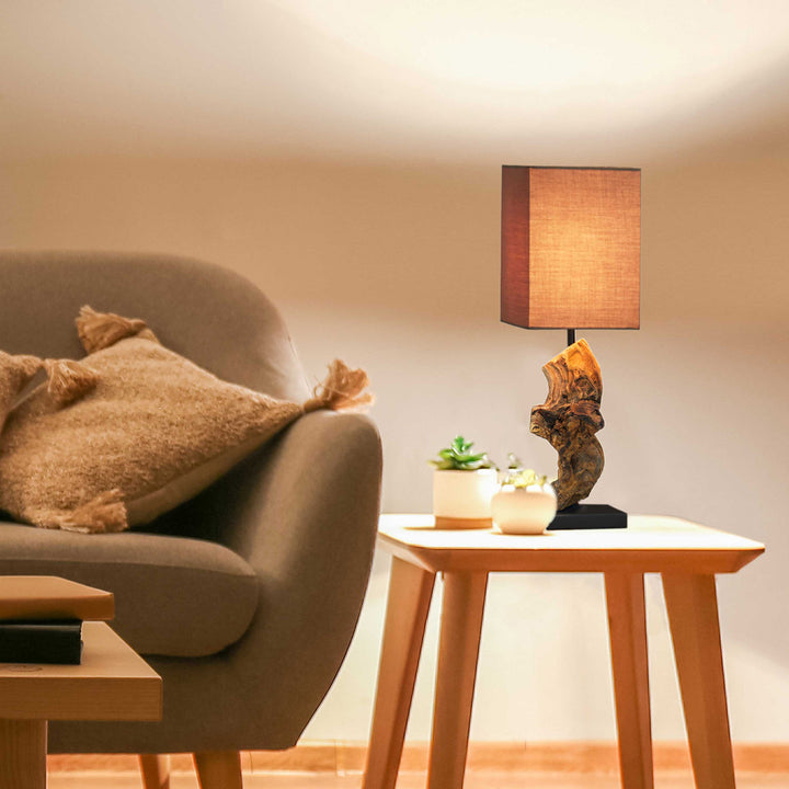 Living room with a gray sofa, wooden side table, and decorative lamp.