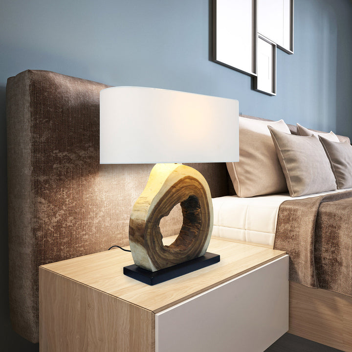 Modern bedroom with a lamp on a nightstand, bed with pillows, and abstract wall art.